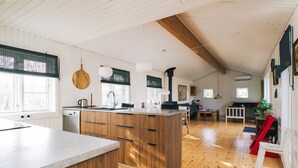 A spacious kitchen with wooden cabinets, a large island, and a dining area with a red chair. - 6 Person Holiday Home in Grevinge (Grevinge)