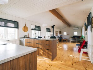 Una cocina amplia con armarios de madera, una isla grande y una zona de comedor con una silla roja.