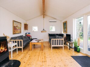 Una sala de estar acogedora con chimenea, dos sofás, una mesa de centro y una televisión.
