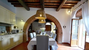 Un espace repas agrémenté d’une arche en briques, d’une nappe blanche et de chaises.