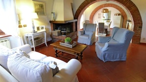 Un salon avec une cheminée, deux fauteuils, un canapé et une table basse.