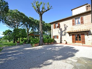 A stone building with a gravel driveway and a large tree in the foreground. - Villa in Tuscany With Pool Near Cortona (Cortona)
