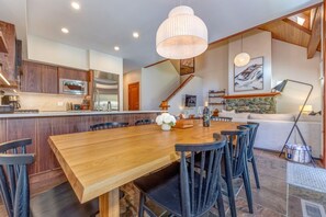 A modern kitchen with a central island, wooden dining table, and black chairs.