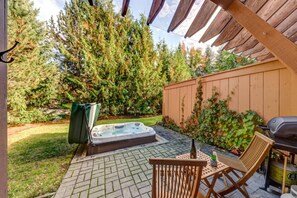 Ein Garten mit Whirlpool, Holzterrasse und überdachter Veranda.