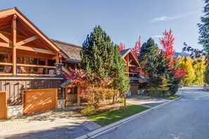 Eine Lodge mit überdachter Veranda, Steineingang und Auffahrt zu einem Parkplatz.