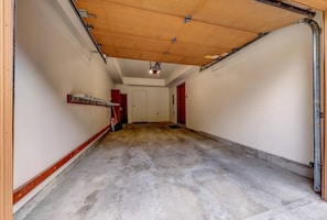 Un garaje con piso de concreto, techo de madera y paredes rojas.