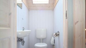 A small, compact bathroom with a white toilet, a sink, and a toilet paper holder. - Skandinavisches Ferienhaus in Mirow (Mirow)