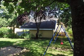 A residential area with a house, a swing set, and a tree. - Ferienhaus im Ferienpark Mirow (Mirow)