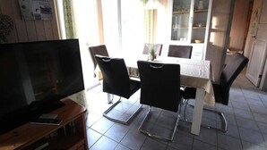 A dining area with a table, chairs, and a television on a stand. - Ferienhaus im Ferienpark Mirow (Mirow)