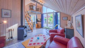 A cozy cabin interior with a wooden interior, a red leather sofa, a fireplace, and a balcony with a view. - Ferienhaus im Skandinavischen Stil (Mirow)