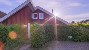 A red house with a sloped roof, surrounded by greenery and a paved driveway. - Ferienhaus im Skandinavischen Stil (Mirow)