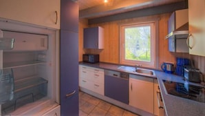 A compact kitchen with a built-in dishwasher, a microwave, and a window providing natural light. - Ferienhaus im Ferienpark Mirow (Mirow)