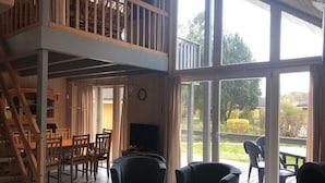 A spacious room with a balcony, wooden furniture, and large windows. - Ferienhaus im Ferienpark Mirow (Mirow)