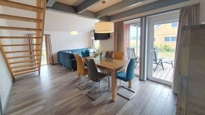 Un coin repas avec une table et des chaises en bois, un canapé et un téléviseur fixé au mur.
