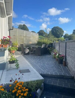 A patio with outdoor furniture, potted plants, and a stone pathway. - Tranquil Countryside Farmhouse Stay (Grangecastle)