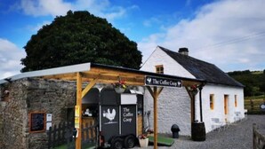 En rustik bygning kaldet "The Coffee Coop" med en facade af sten, en træveranda og et skilt.