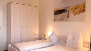 A bedroom with a bed, a wardrobe, a nightstand with a lamp, and a painting on the wall. - Marina View Comfort Stay (Rechlin)