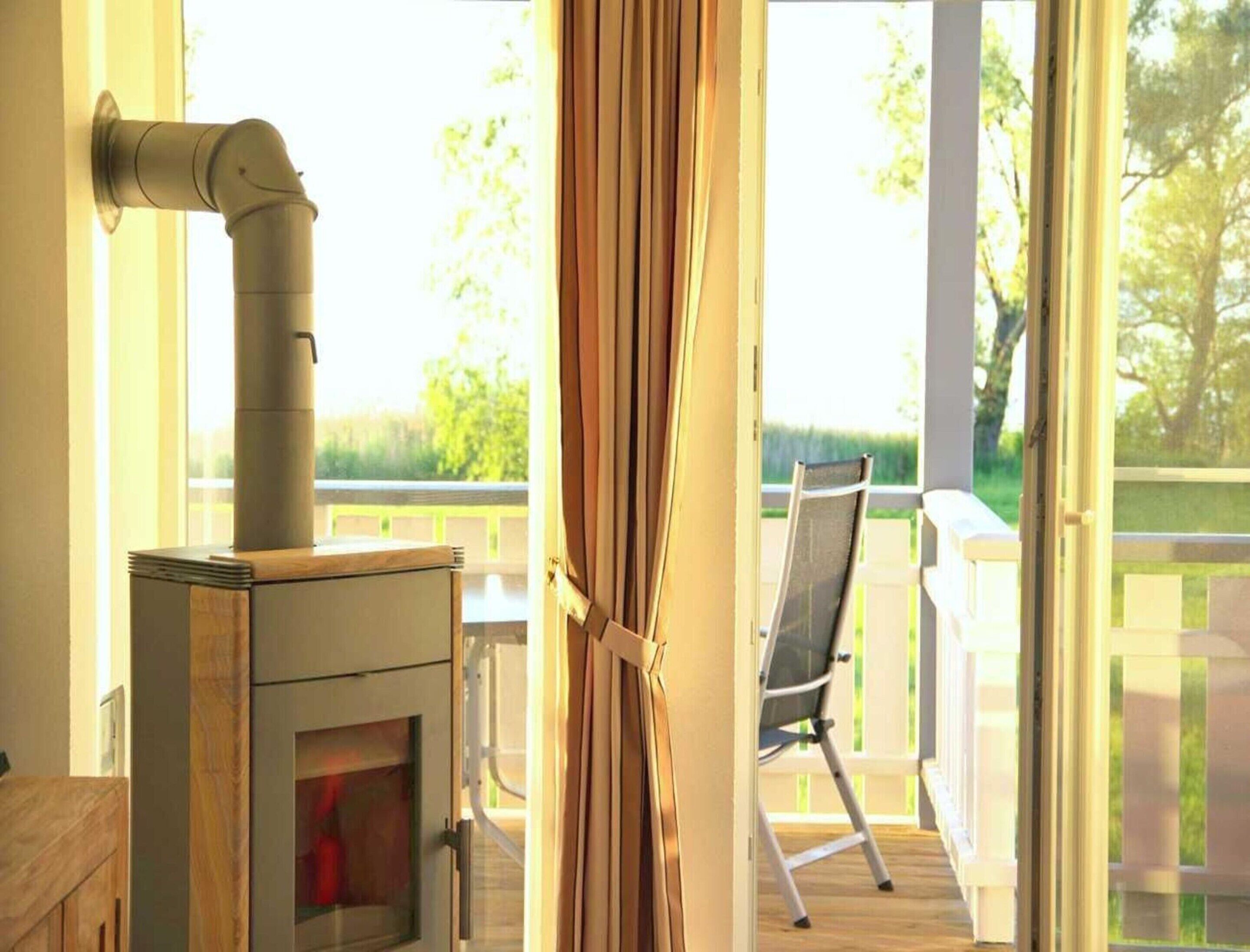 A room with a wood-burning stove, a sliding glass door leading to an outdoor deck, and a chair facing the deck.