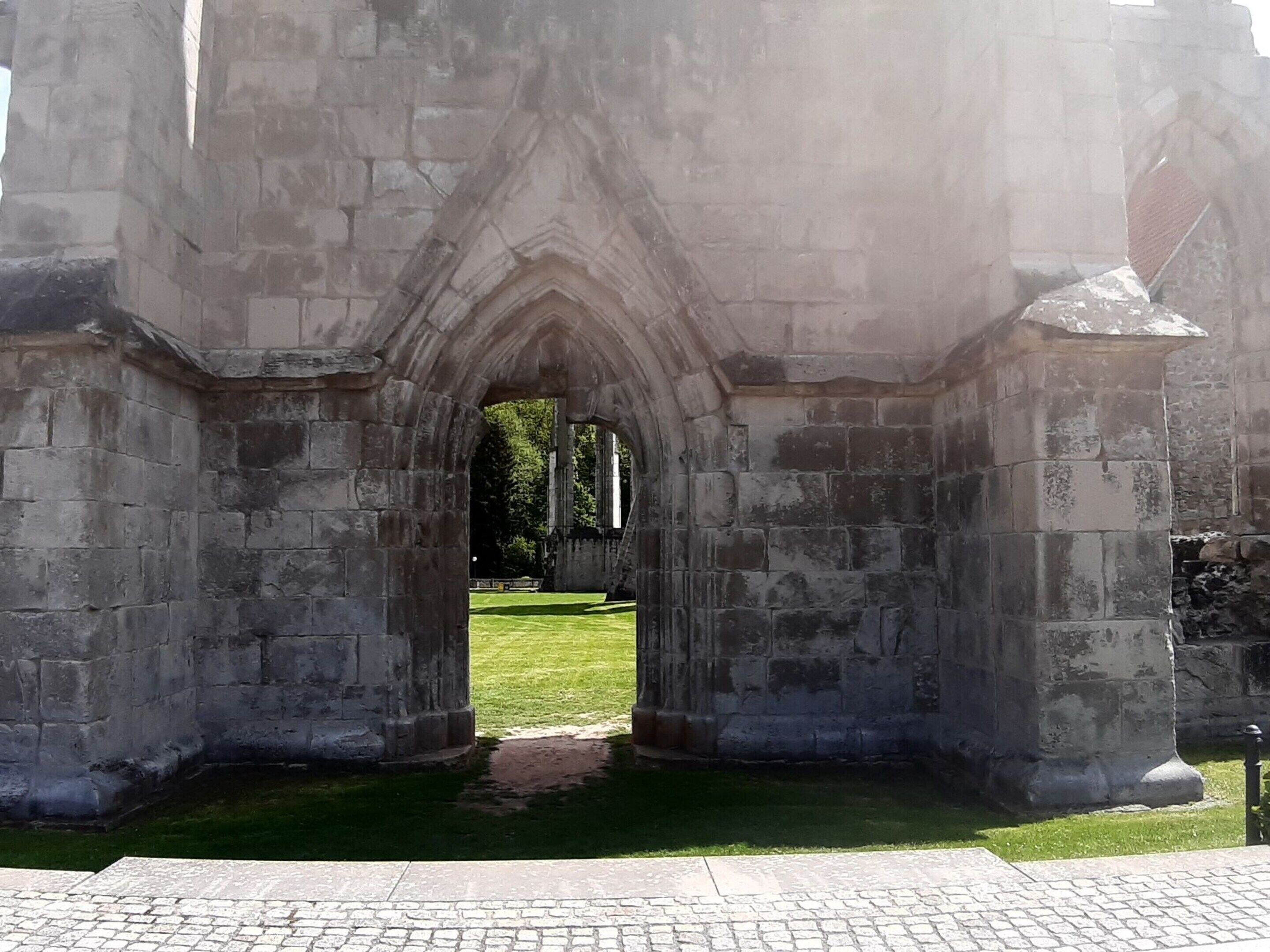 Uma estrutura de pedra em arco com uma área gramada na frente.
