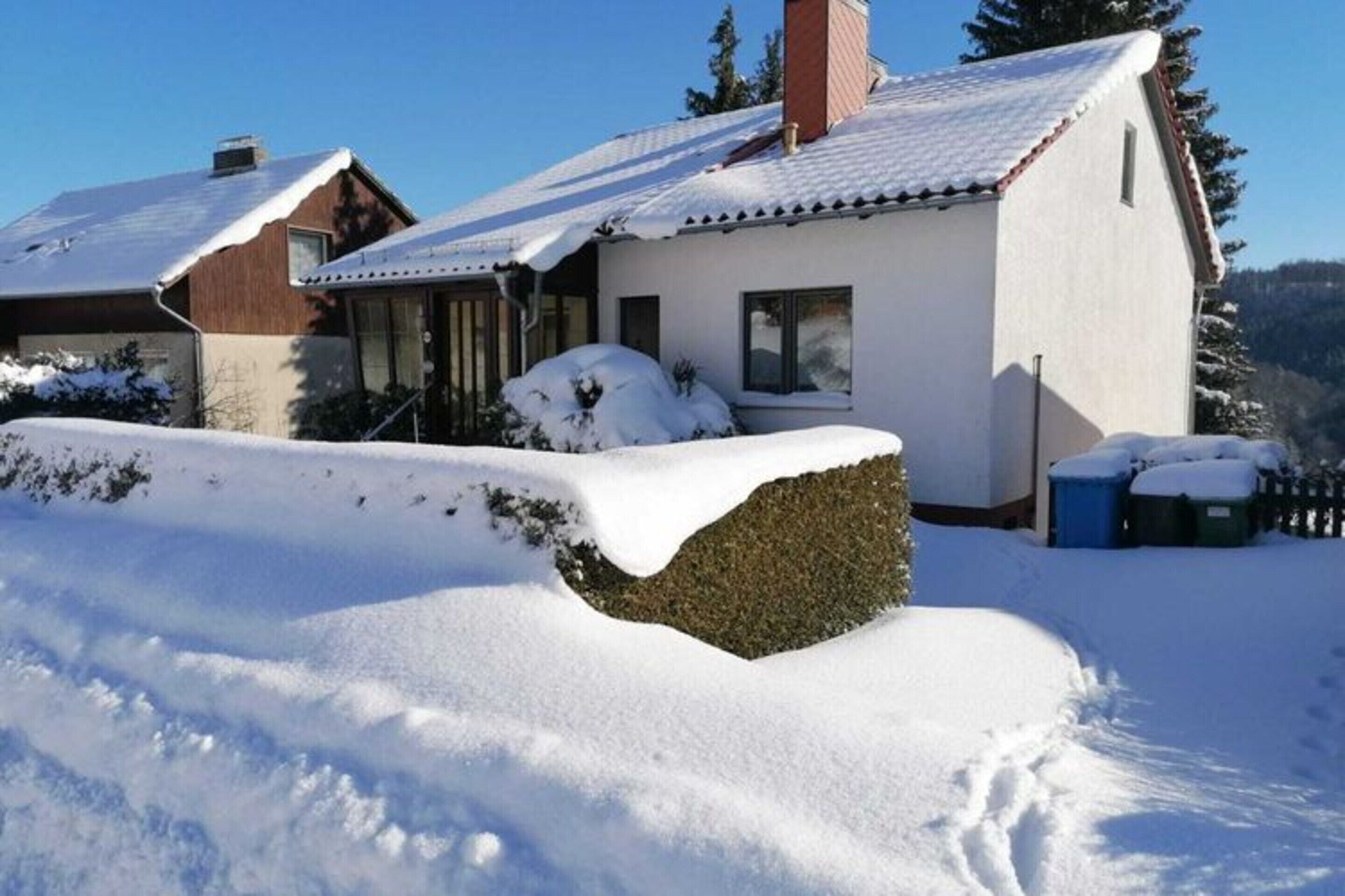 Et snedækket hus med skrå tag, skorsten og en lille veranda.