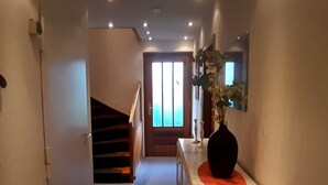 Ein Flur mit Treppe, einer Blumenvase und einem Fenster mit Jalousien.