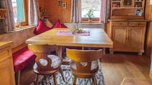 A wooden interior with a dining table, chairs, a bench, a kitchen area, and a window with curtains. - Chalet Near Passthurn Ski Area Kitzbuhel (Mittersill)