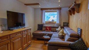A living room with a television, wooden cabinets, a sofa, and a window with a view. - Chalet Near Passthurn Ski Area Kitzbuhel (Mittersill)