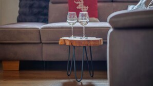 A wooden table with two wine glasses on it, placed in front of a sofa with a red pillow. - Chalet Near Passthurn Ski Area Kitzbuhel (Mittersill)
