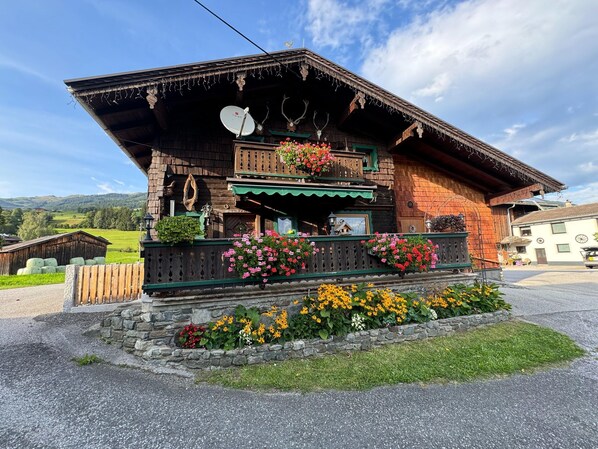 A traditional wooden building with a sloped roof, a balcony with flower boxes, and a stone foundation. - Chalet Near Passthurn Ski Area Kitzbuhel (Mittersill)