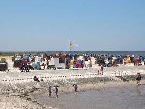 Ein Strand mit vielen bunten Strandkörben und einer Rettungswache.