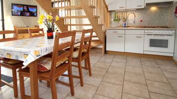 A modern kitchen with white cabinets, a built-in oven, and a wooden staircase.