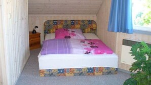 Ein kleiner, gemütlicher Raum mit einem Bett, einem Nachttisch und einem Fenster mit Vorhang.