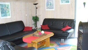 Ein Wohnzimmer mit einer schwarzen Ledersofa, einem Holztisch und einem bunten Teppich.