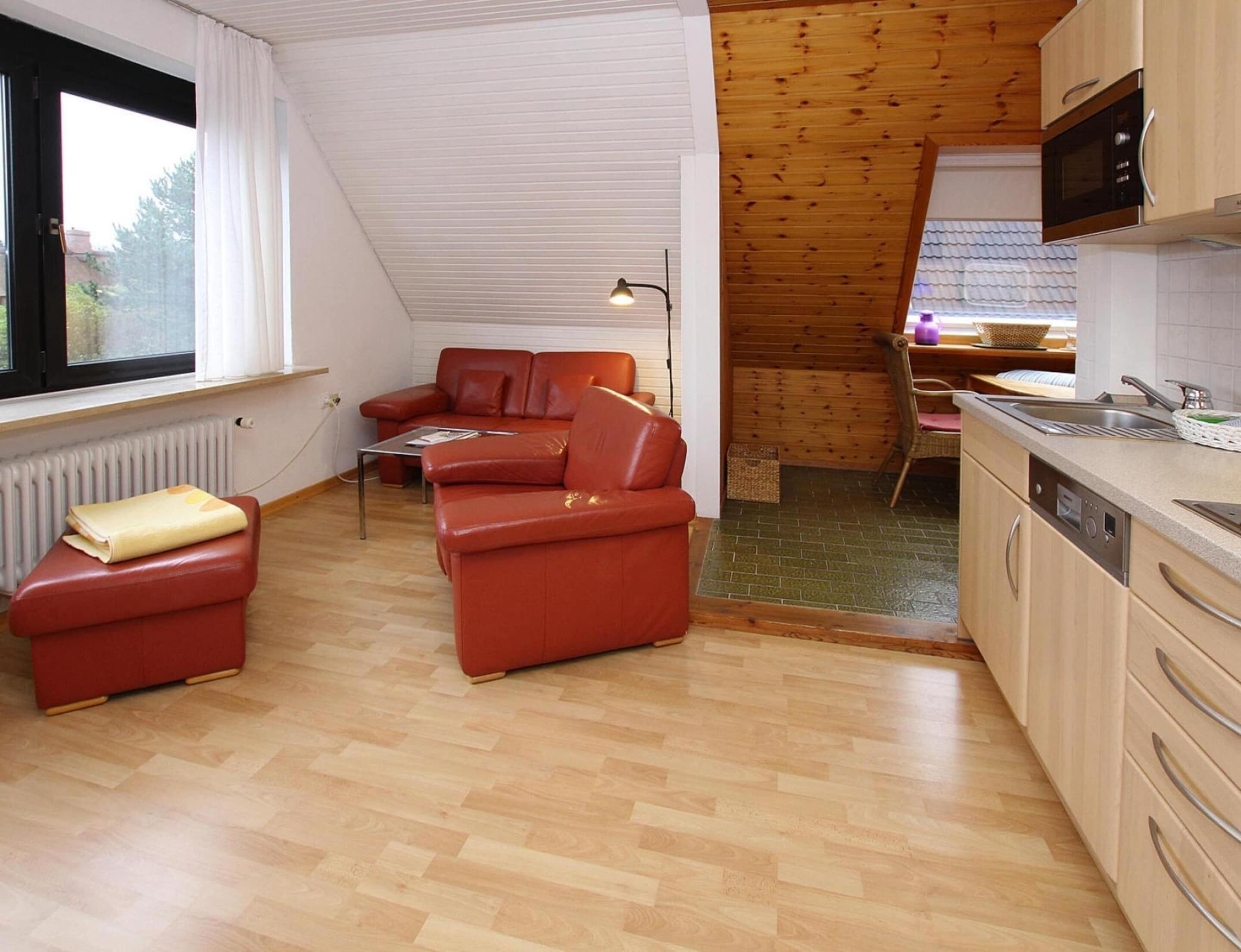 A compact living space with a kitchenette, a sofa, a dining area, and a window with curtains.