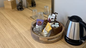 A wooden table with a tray holding tea bags, a kettle, and a small figurine.