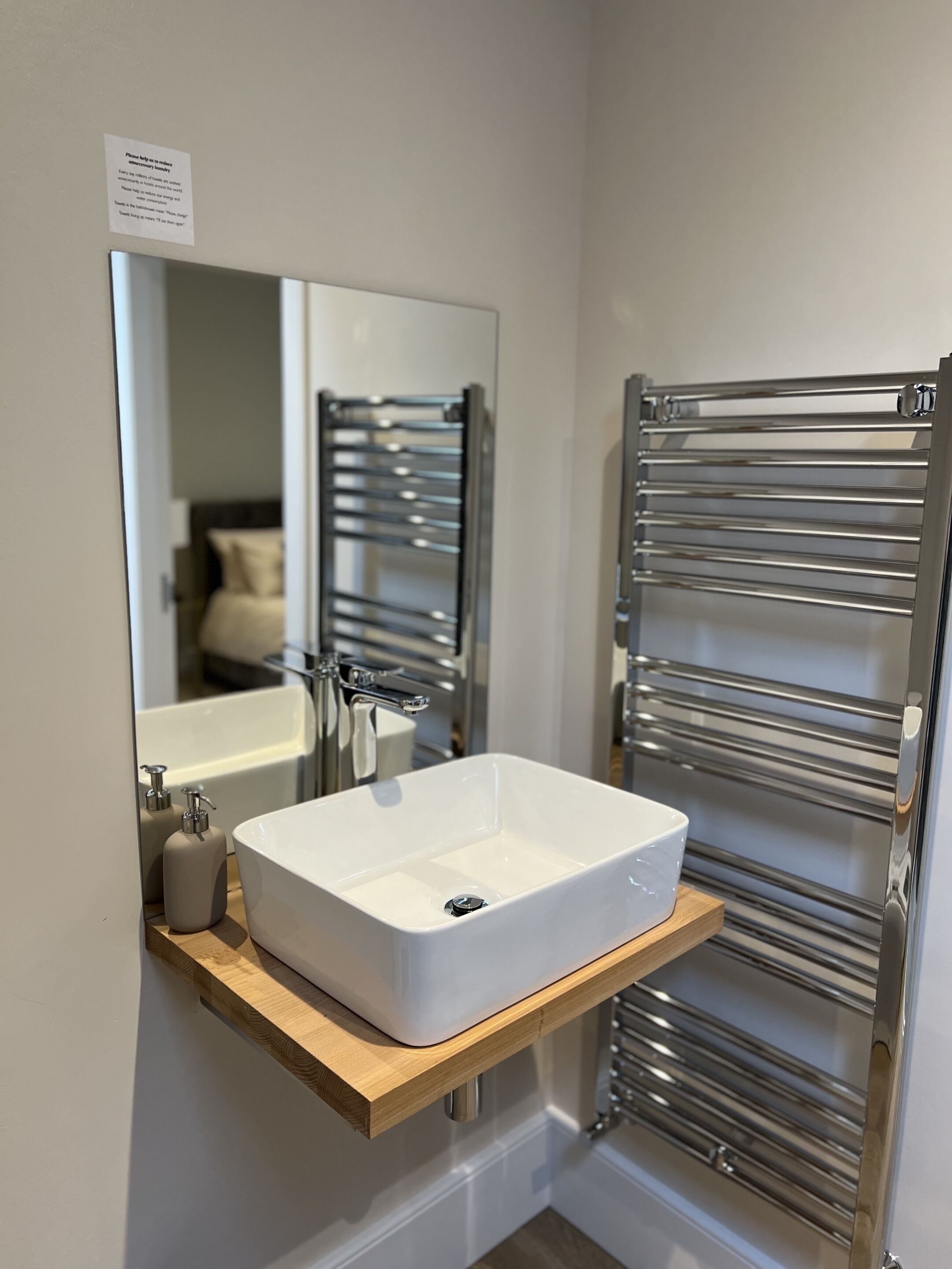 A modern bathroom with a white sink, a mirror, and a towel rack.