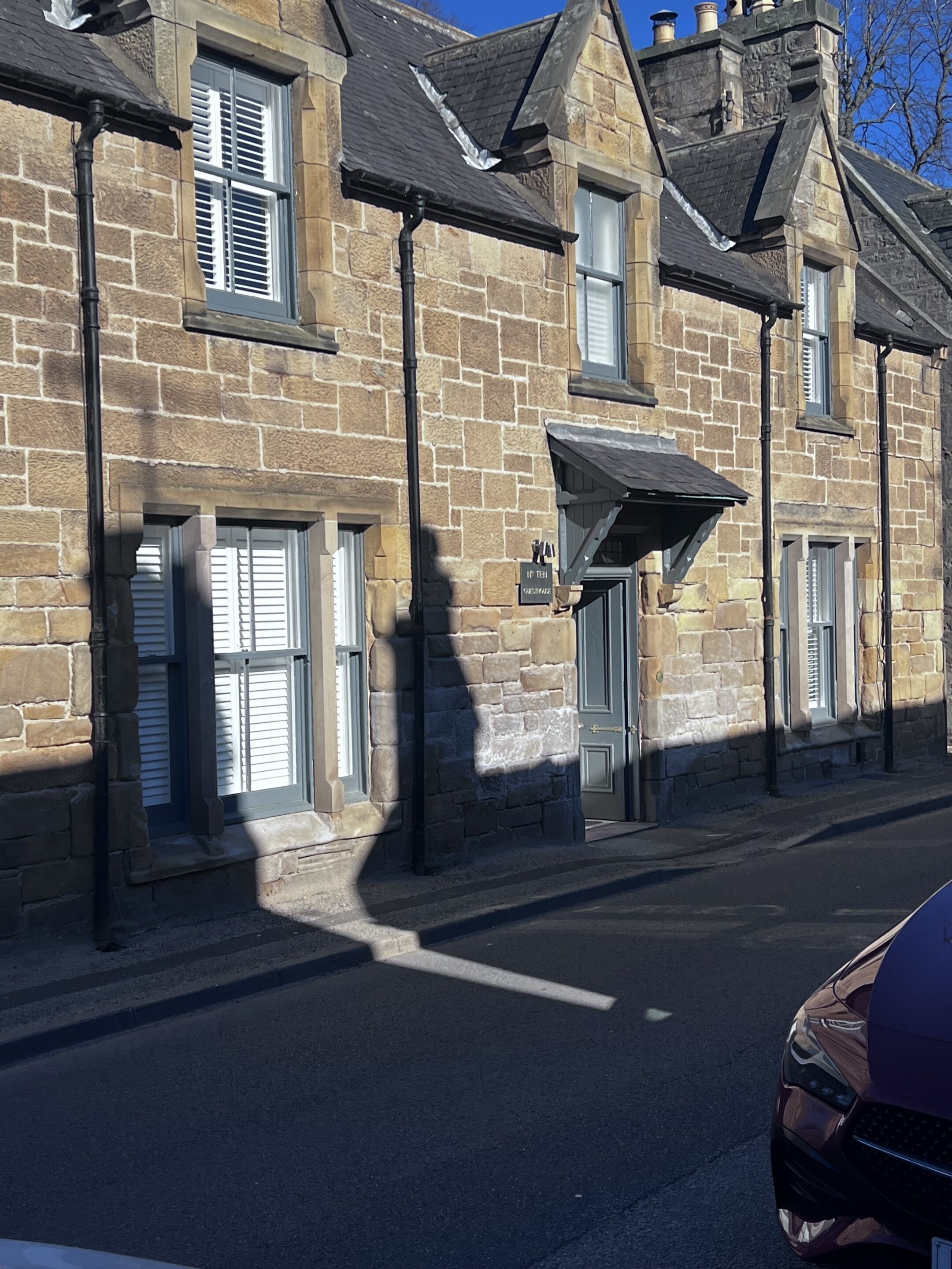 Eine Reihe von Steinhäusern mit traditioneller Architektur, mit mehreren Fenstern und Türen, und eine klare Straße davor.