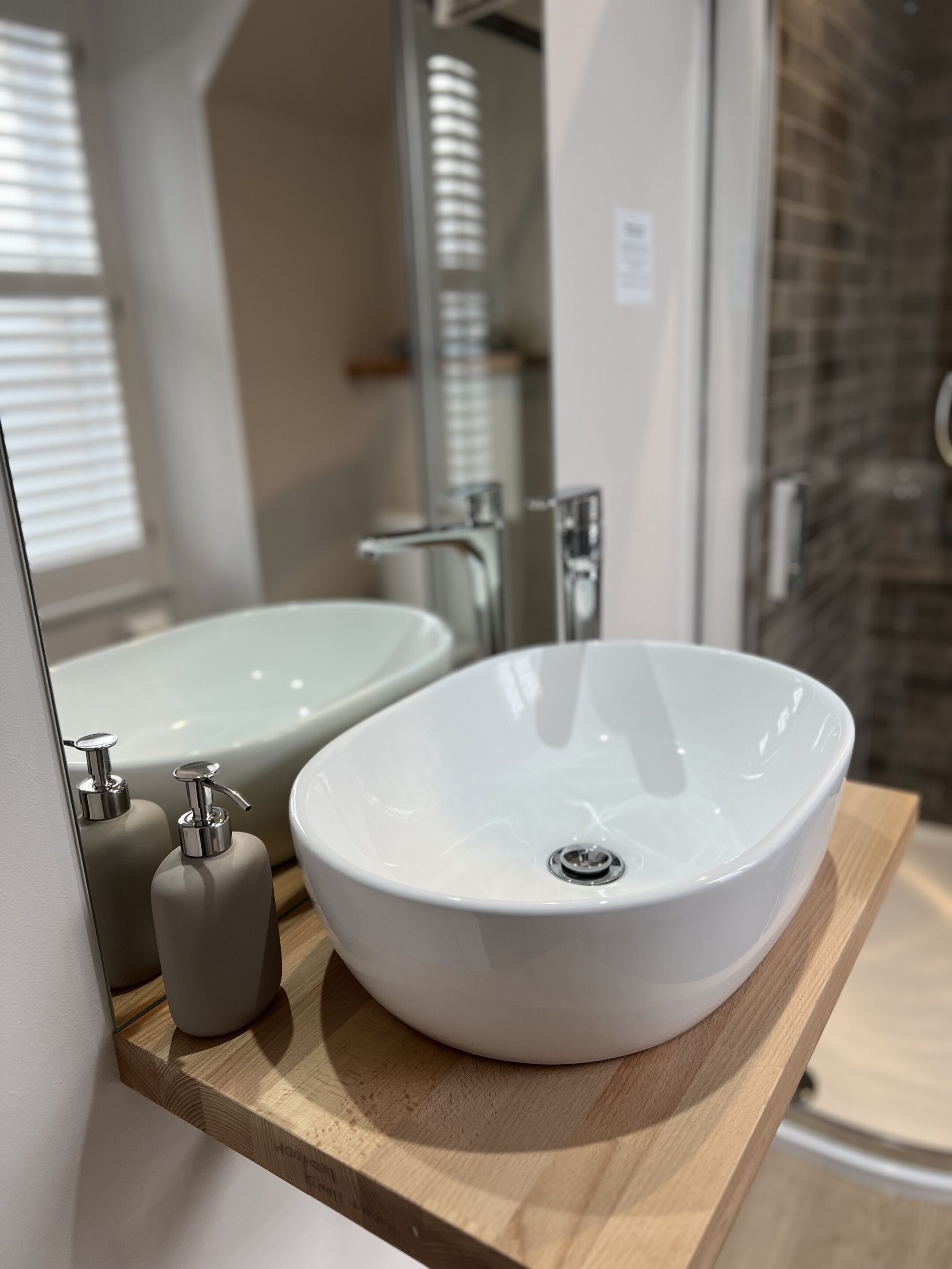 Un baño con un lavamanos blanco ovalado, un espejo y una encimera de madera.