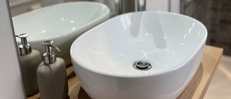 Un baño con un lavamanos blanco ovalado, un espejo y una encimera de madera.