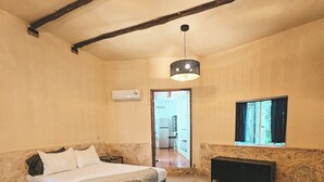 Un dormitori amb un llit, una tauleta de nit, una catifa, un televisor i una finestra.