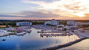A marina with multiple boats docked, surrounded by buildings and a sunset in the background. - Blockhaus im Ostseeresort Dampland (Damp)