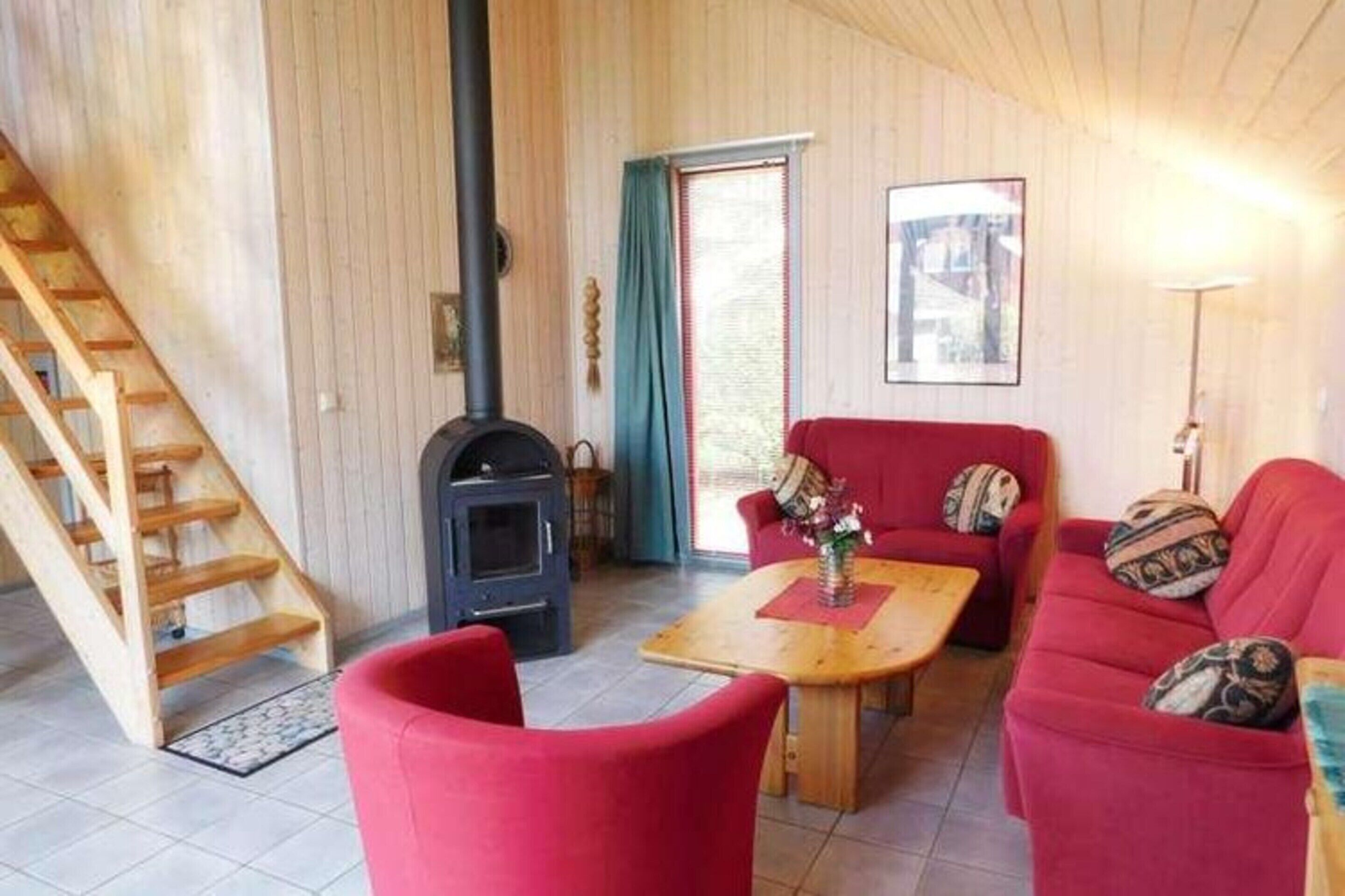 Un salon chaleureux avec un canapé rouge, une table basse en bois et une cheminée.