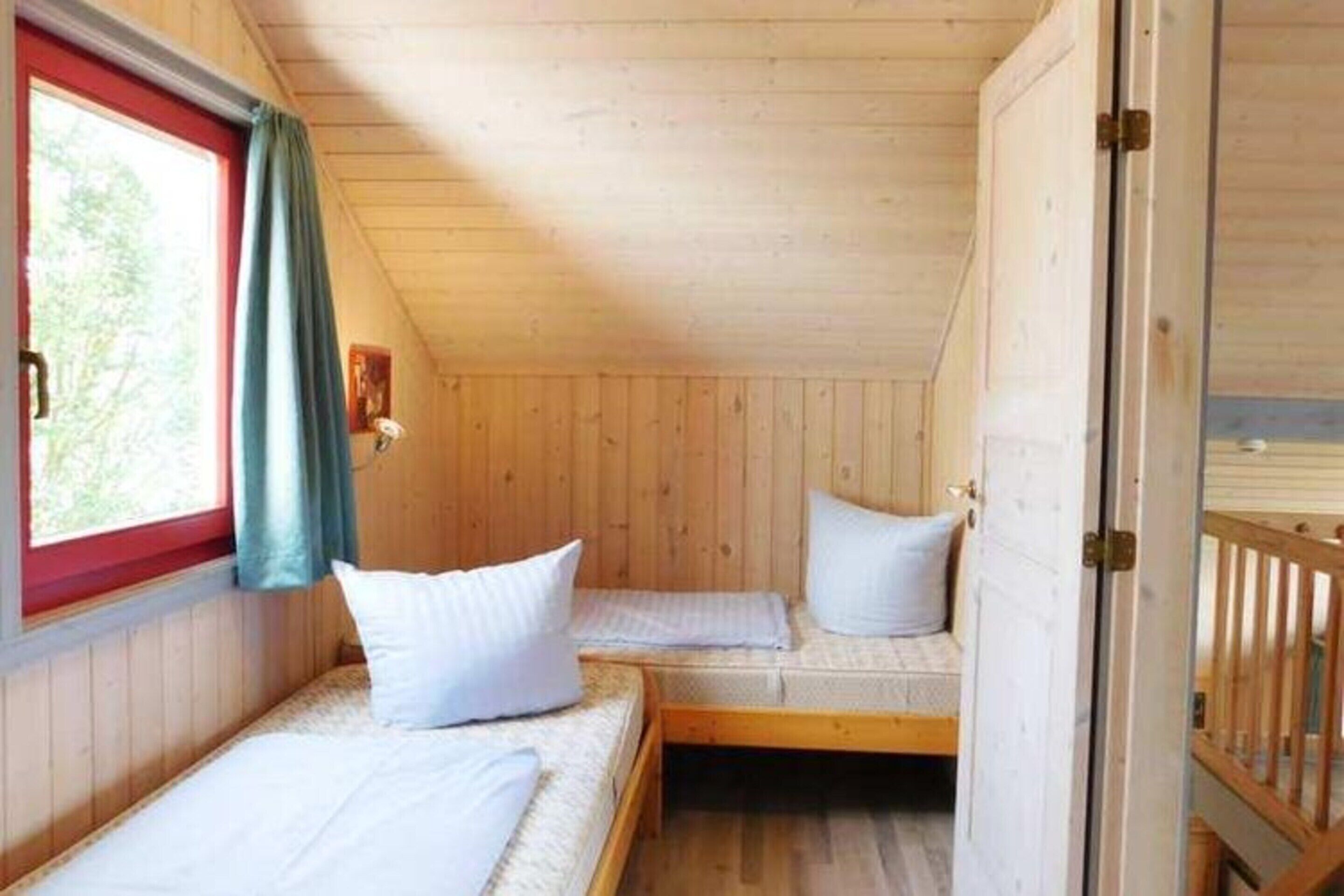 A cabin with two bunk beds, wooden walls, and a window with curtains.
