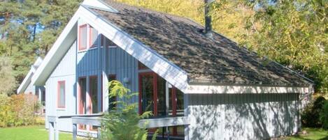 A small, single-story house with a sloped roof, a front porch, and a chimney.