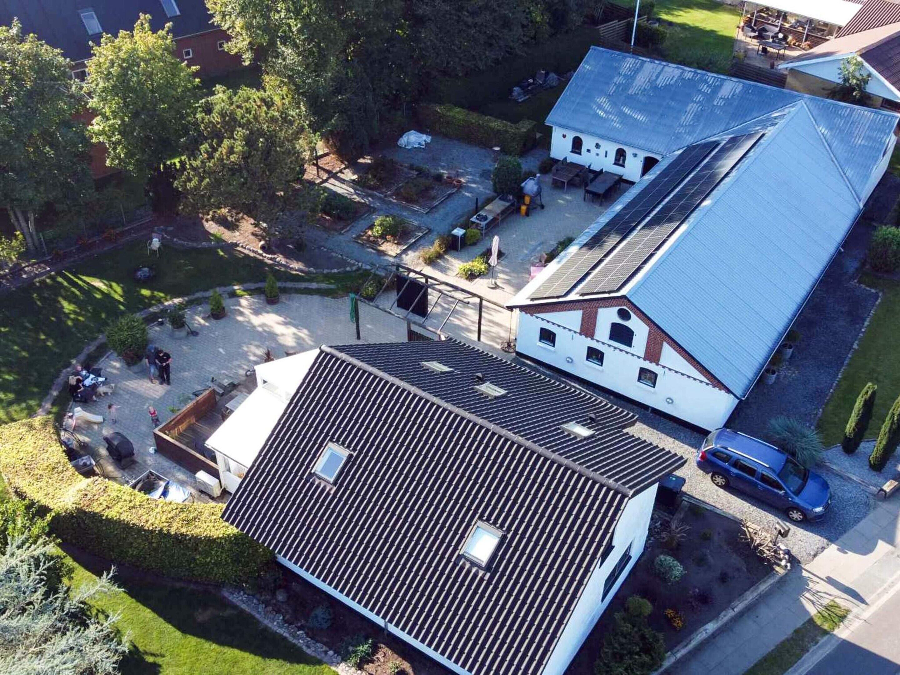 Zona residencial con una casa de techo inclinado, patio cercado y pequeño jardín.