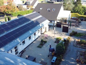 A residential area with a house featuring a solar panel roof, a barbecue setup, and a paved patio. - 4 Star Holiday Home in Frederikshavn (Frederikshavn)