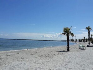 A beach with a clear sky, calm sea, and a few palm trees. - 4 Star Holiday Home in Frederikshavn (Frederikshavn)
