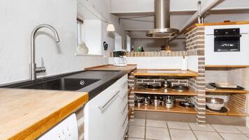 Una cocina moderna con encimera negra, electrodomésticos de acero inoxidable y una pared de ladrillo decorativa.