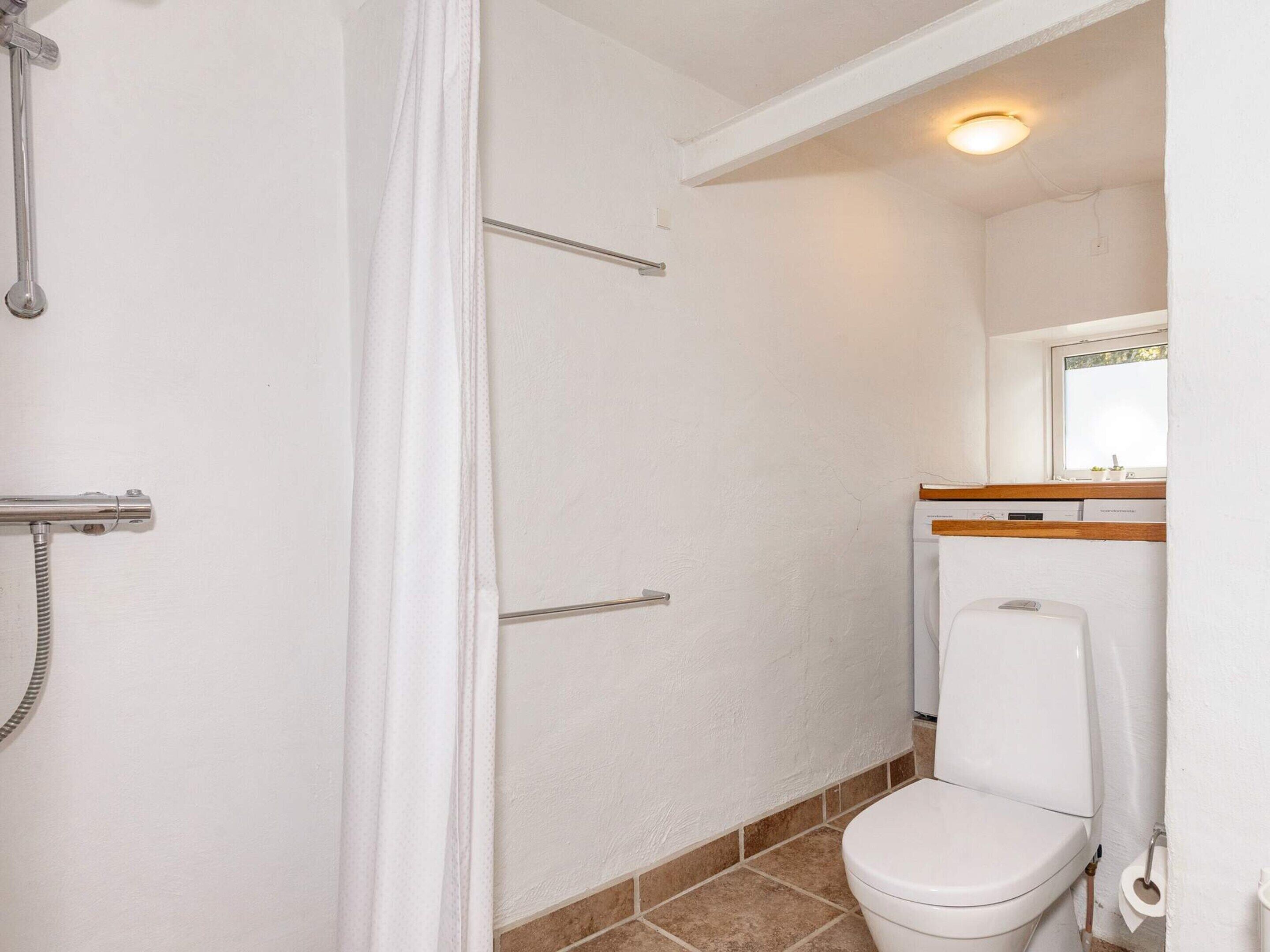 Ein Badezimmer mit Toilette, Dusche und Handtuchhalter.