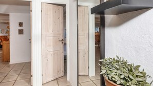 A hallway with a wooden door, a potted plant, and a black shelf with decorative items. - 4 Star Holiday Home in Frederikshavn (Frederikshavn)